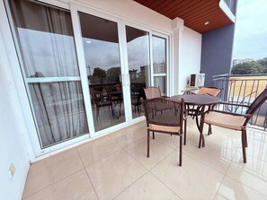 A balcony with a table and chairs, a sliding glass door, and a view of the cityscape. - East Legon 1BR·2 Balconies·Pool·Gym·Backup Power (Accra)