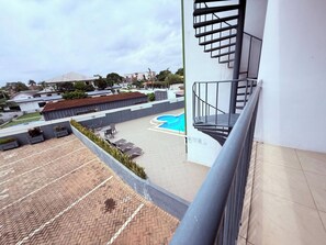A rooftop with a swimming pool, outdoor seating, and a staircase. - East Legon 1BR·2 Balconies·Pool·Gym·Backup Power (Accra)