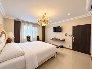 Ein Hotelzimmer mit einem großen Bett, einer Chandelier, einem Fernseher und einem Kleiderschrank.