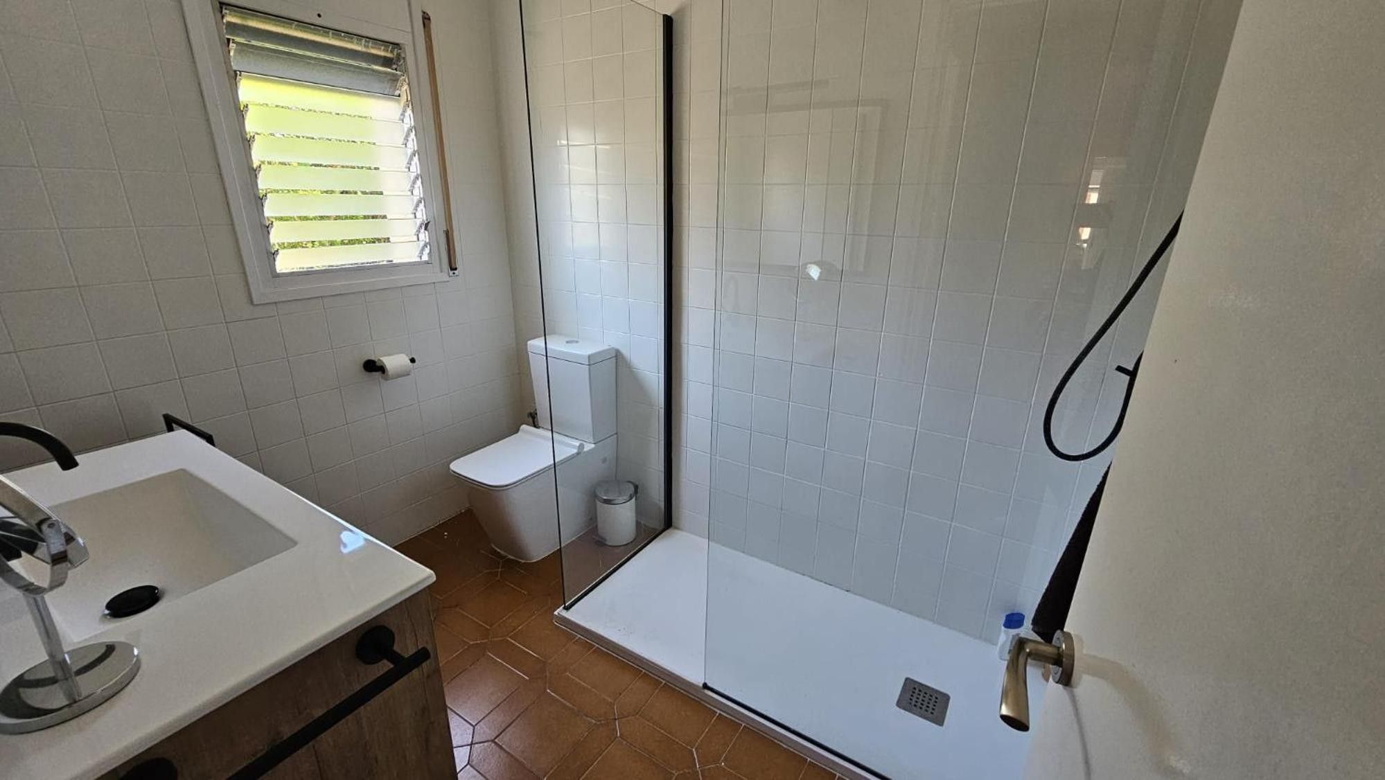 A bathroom with a shower, toilet, and sink.