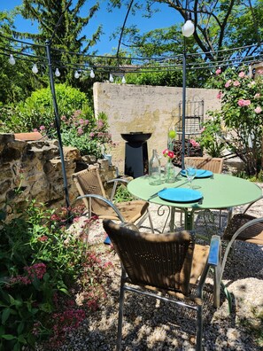 Eine Außenpatio mit einem runden Tisch, Korbstühlen und einer Steinwand.