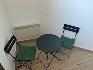 Une petite pièce avec une table ronde et deux chaises dotées d’assises rembourrées.