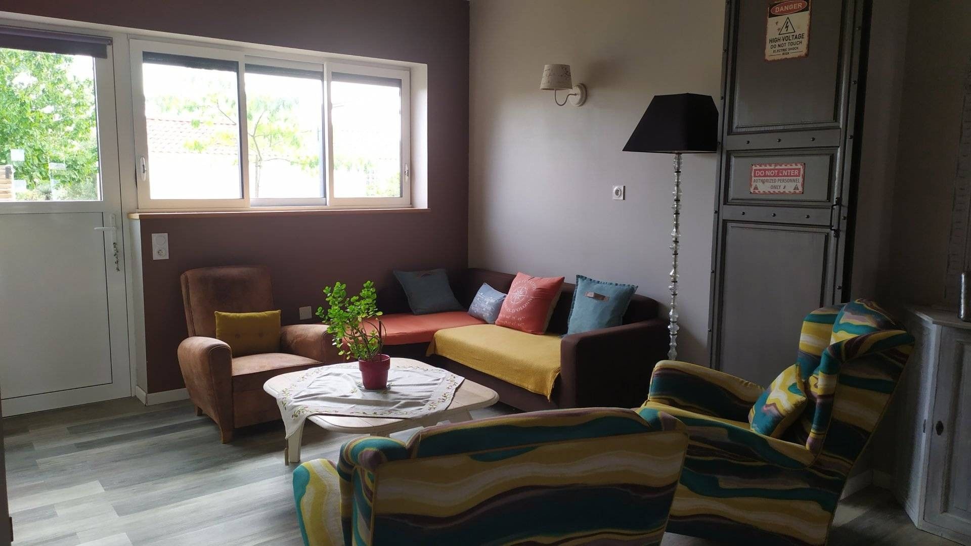 A living room with a sofa, armchairs, a coffee table, and a potted plant.