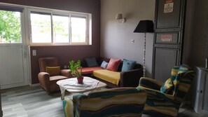 A living room with a sofa, armchairs, a coffee table, and a potted plant.