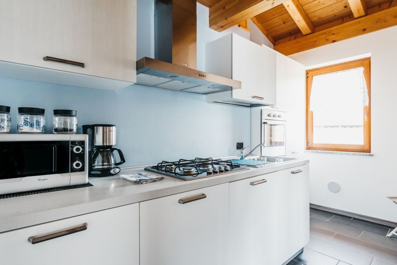Una cucina moderna con mobili bianchi, un piano cottura a gas, un forno a microonde e una macchina per il caffè.