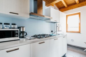 Una cucina moderna con mobili bianchi, un piano cottura a gas, un forno a microonde e una macchina per il caffè.