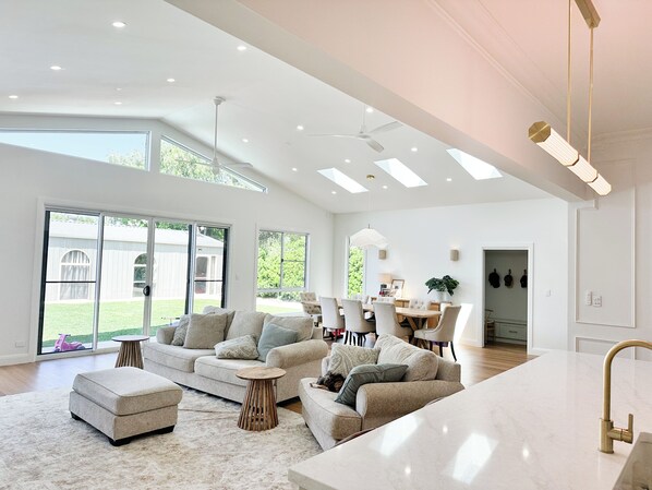 A spacious living room with a large sofa set, a dining area, and a kitchen with a marble countertop.