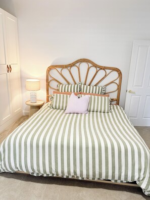 A bed with a striped bedspread, a wooden headboard, and a bedside lamp.