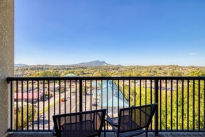 A balcony with two chairs overlooking a parking lot and a view of a mountain range. - Mountains View Condo, Pool Access, WIFI (Pigeon Forge)
