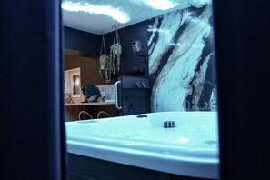 A bathroom with a marble wall, a bathtub, and a hanging plant. - New Listing (Breuschwickersheim)