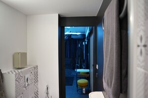 Un passadís estret amb una porta que condueix a una habitació amb un llit i una taula petita.