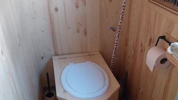 Un bagno compatto e ottagonale in legno, con un rotolo di carta igienica sulla destra.