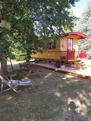 Eine Holzhütte mit rotem Dach, einem Picknicktisch und einer Bank.