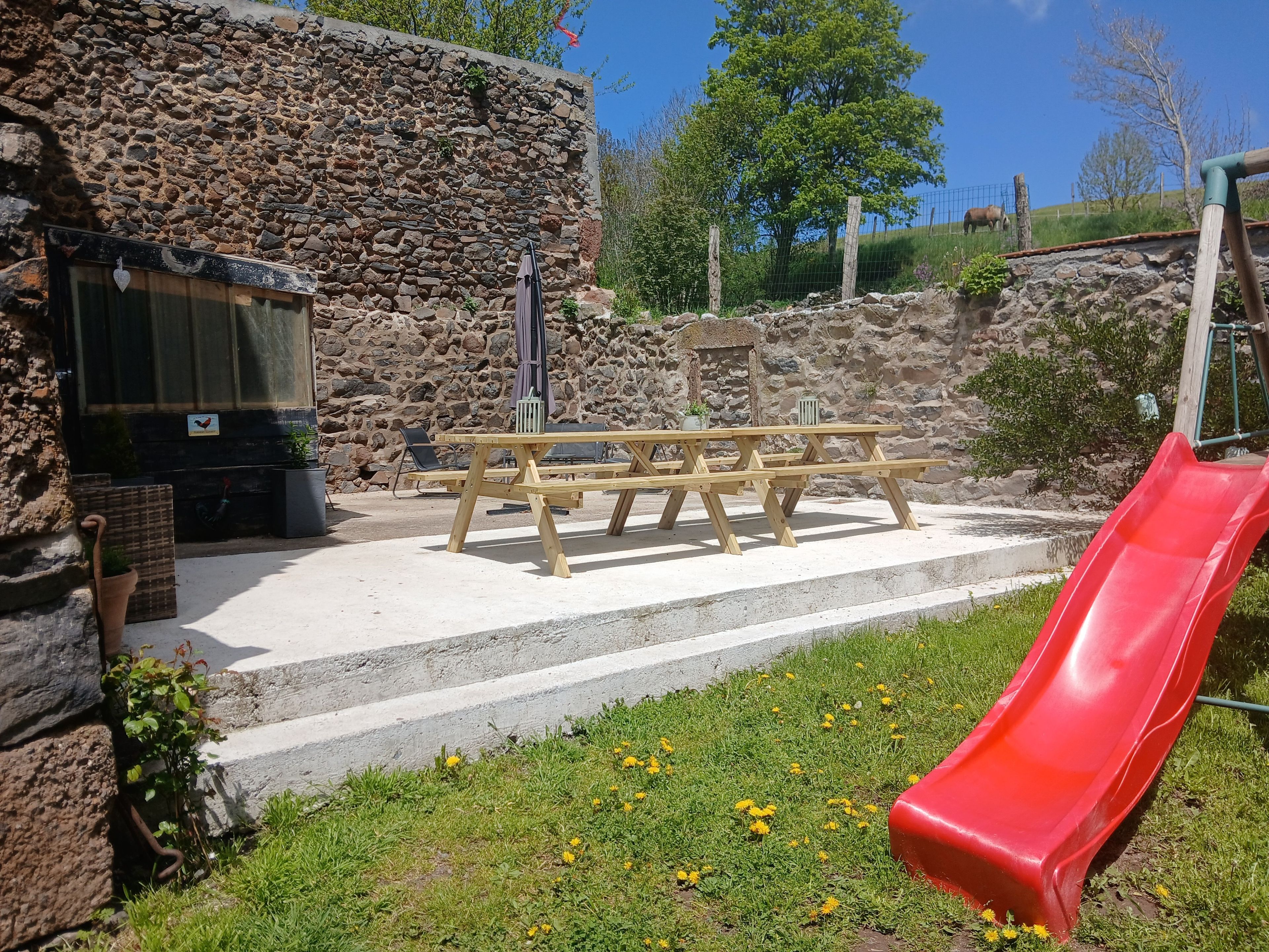 Un espace pique-nique avec des bancs et un toboggan rouge.