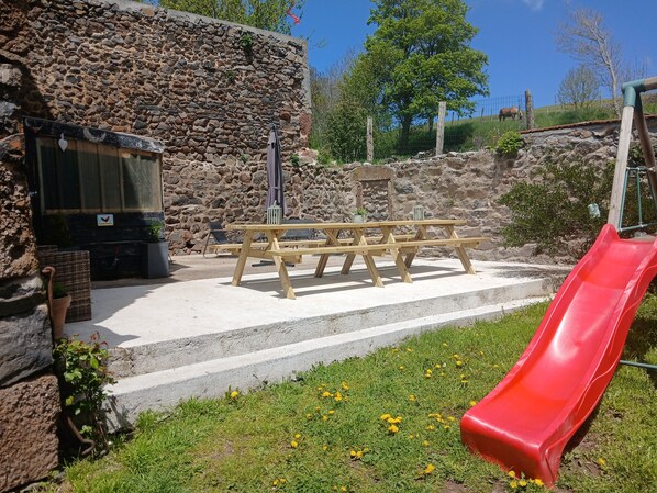 Un espace pique-nique avec des bancs et un toboggan rouge.