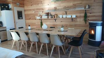 Un intérieur chaleureux en bois, avec une table à manger, des chaises, une cheminée et un coin cuisine.