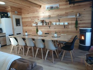 Un intérieur chaleureux en bois, avec une table à manger, des chaises, une cheminée et un coin cuisine.