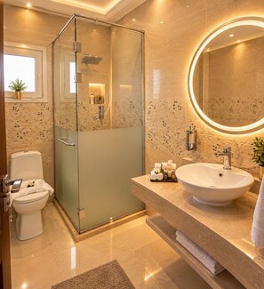 A modern bathroom with a glass-enclosed shower, a large sink, and a round mirror. - Arkan Egyptian Museum Hotel (Giza)