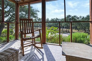 A wooden chair in a room with large windows overlooking a vineyard.