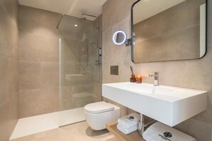 Un bagno moderno con cabina doccia in vetro, lavandino bianco e un grande specchio con illuminazione ad anello.