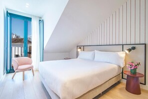 Camera da letto moderna con un letto grande, una sedia, un comodino con una lampada e vista panoramica attraverso una porta vetrata.