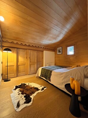 A wooden-paneled room with a bed, a floor lamp, a framed picture, and a small window. - New Listing (Praz-sur-Arly)