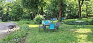 Un área de estar al aire libre con una mesa y sillas, rodeada de follaje y árboles.