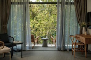 A room with a view of a forest through large windows, a dining table, and two chairs. - SENDORO RETREAT (Thanh pho Ho Chi Minh)