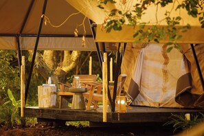 A tent with a wooden table, chairs, and a hanging light fixture. - SENDORO RETREAT (Thanh pho Ho Chi Minh)