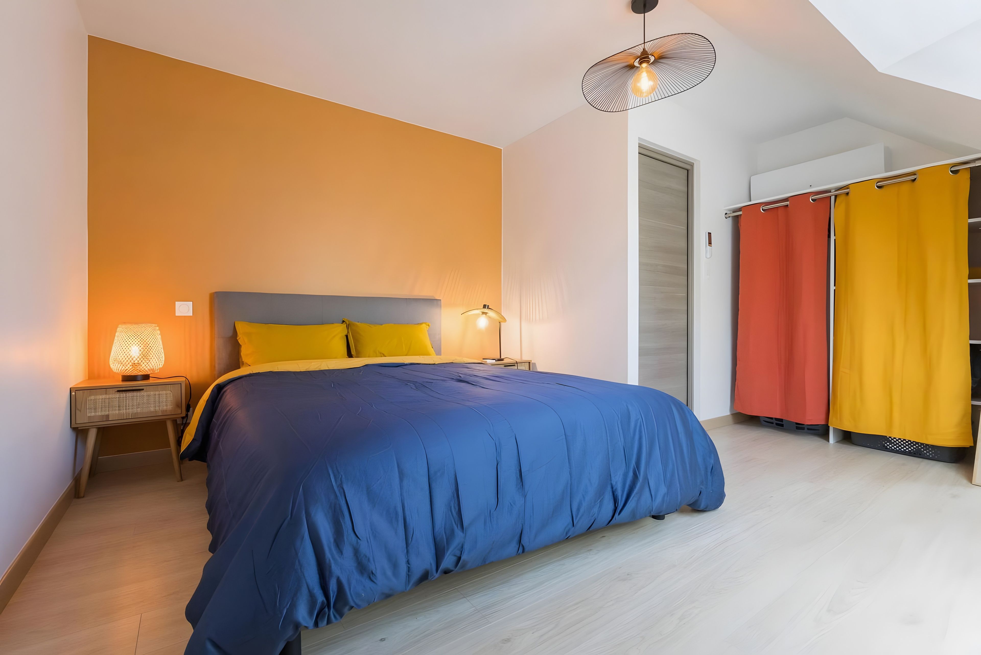Une chambre à coucher avec un lit, deux lampes de chevet, une table de chevet et une armoire avec des rideaux.