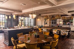 Um restaurante com um bar central, várias mesas de jantar e cadeiras.