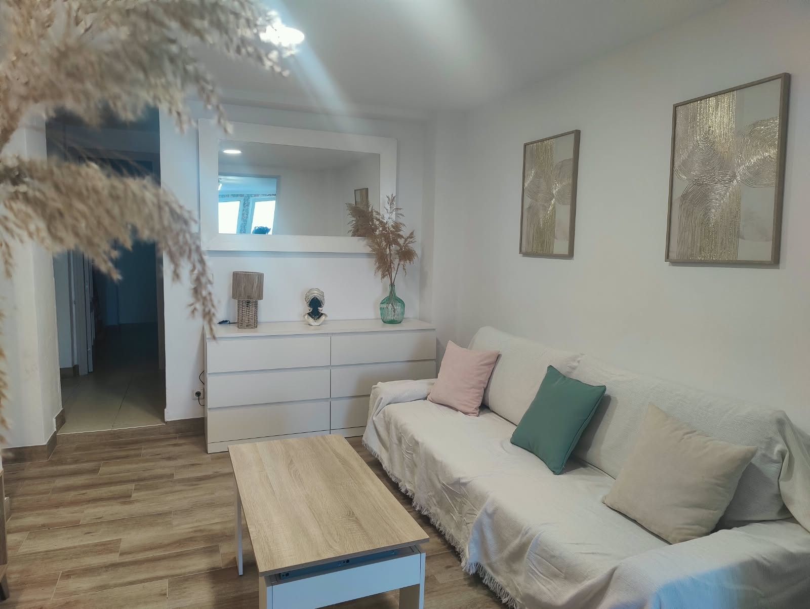 Een moderne woonkamer met een bank, een salontafel en een console met decoratieve objecten.