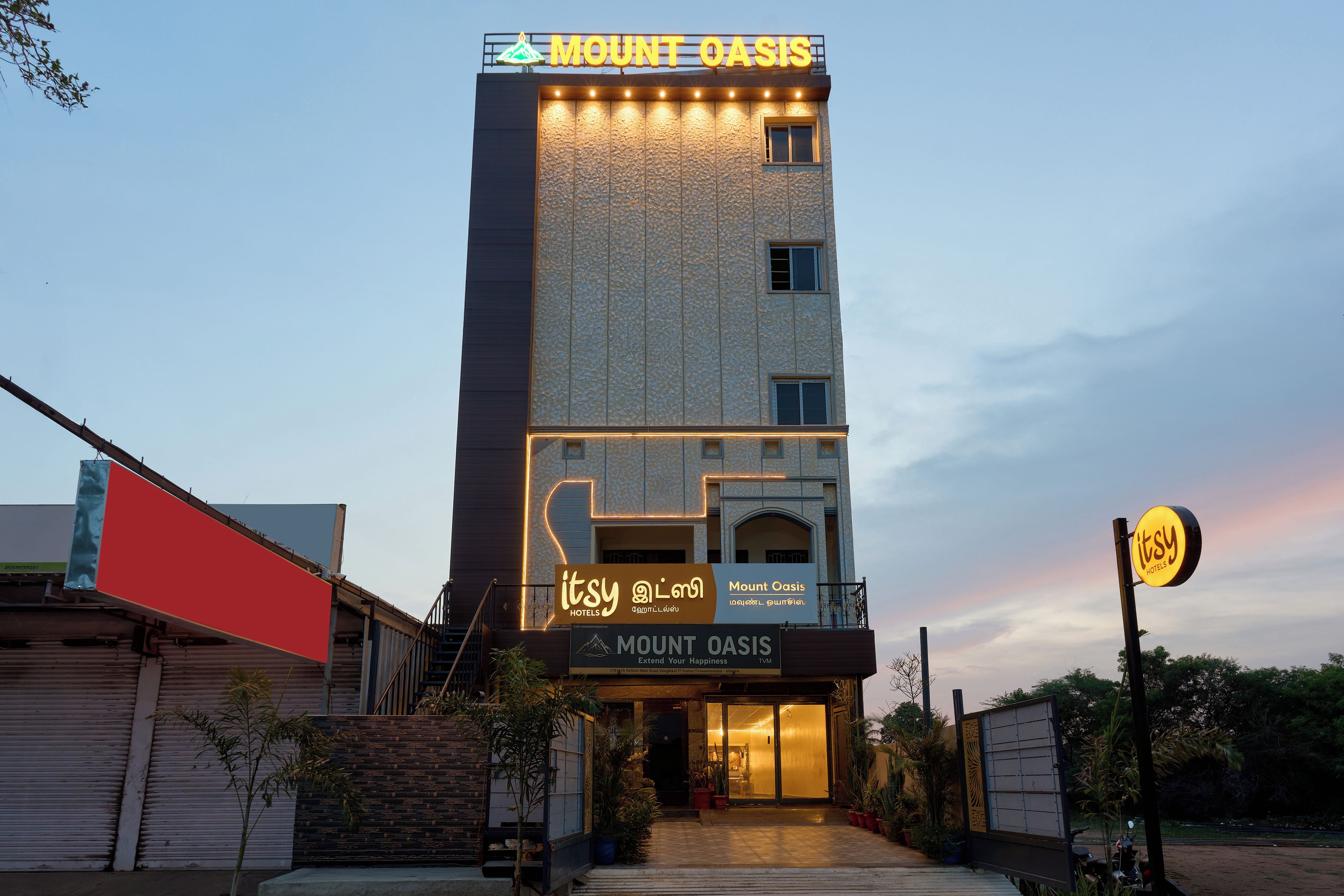 A hotel named Mount Oasis with a signboard and a neon sign for Itsy Hotels.