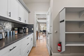 A modern kitchen with white cabinets, a black countertop, and a hexagonal backsplash. - 3BR Main & Upper Floor in Airdrie | Sleeps 9 | Canal View (Airdrie)
