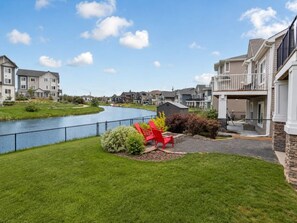A residential area with a river, red Adirondack chairs, and a small shed. - Private Walkout Basement Suite in Airdrie | Sleeps 2 | Pool Table (Airdrie)