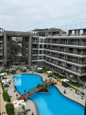 A modern residential building with a swimming pool and outdoor seating area. - Zen Cantonments Studio · WiFi, Pool, Gym & Balcony (Accra)