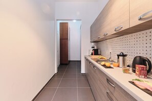 Una cuina moderna amb una illa central, una cafetera i un bullidor al taulell.