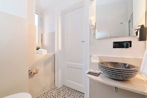 A bathroom with a white door, a sink with a large bowl, a mirror, and a towel rack. - New Listing (Roma)