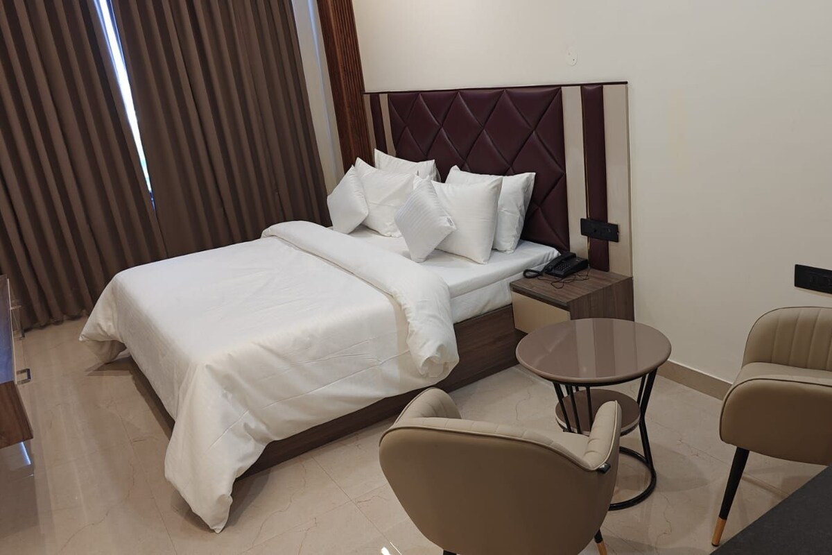 Une chambre d’hôtel avec un lit, une table de chevet, une lampe et deux chaises.