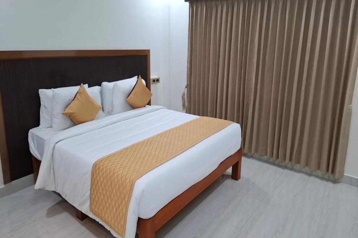 Een hotelkamer met een bed, gordijnen en een houten hoofdeinde.
