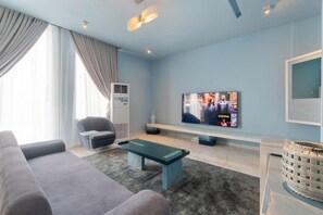 Uma sala de estar moderna com um sofá, uma mesa de centro, uma televisão e uma lareira.