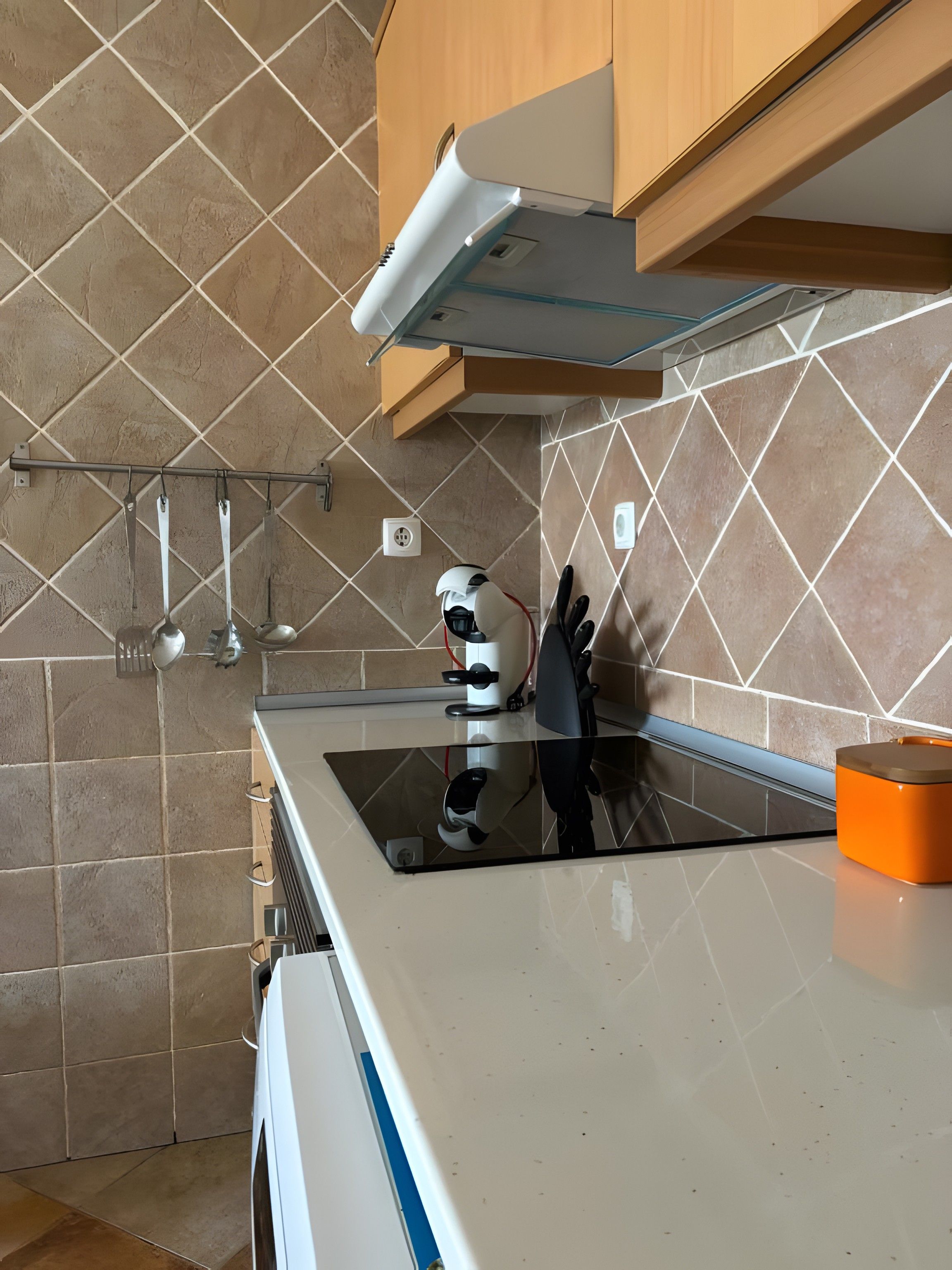 Modernilla designilla varustettu keittiö, jossa on ruostumattomasta teräksestä valmistettu liesituuletin, sisäänrakennettu uuni ja työtaso, jossa on pesuallas.
