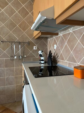 Modernilla designilla varustettu keittiö, jossa on ruostumattomasta teräksestä valmistettu liesituuletin, sisäänrakennettu uuni ja työtaso, jossa on pesuallas.
