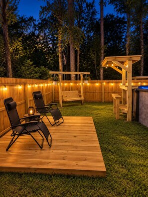 A wooden deck with a pergola, string lights, and outdoor furniture. - Eclectic Tiny Home, Private Hot Tub, Shared Pool, In Between Beach & Downtown (Wilmington)