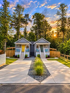 Une maison à deux étages avec un porche à l’avant, un petit jardin et une clôture en bois.