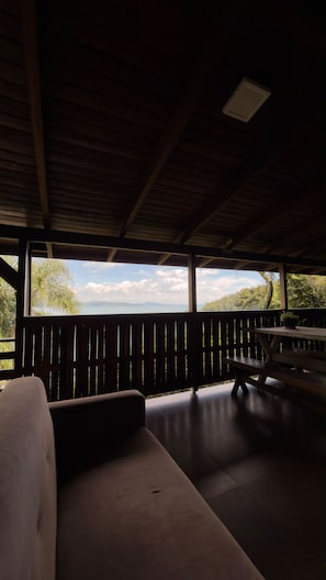 Ein Innenraum mit Holzboden, einer Bank und Blick auf eine Naturlandschaft.