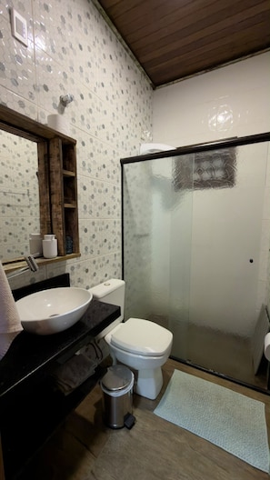 Ein Badezimmer mit Toilette, Waschbecken und einer Dusche mit Glastür.