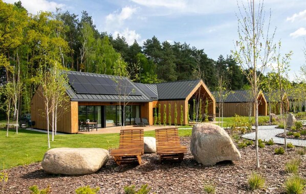A modern cabin with a glass facade, wooden deck, and outdoor seating. - Cozy home in Lawica with sauna (Lawica)