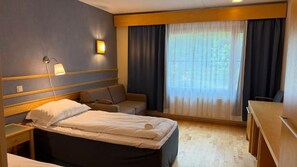 A hotel room with a bed, a sofa, a desk, and a window with curtains. - Tiera Resort (Taivalkoski)