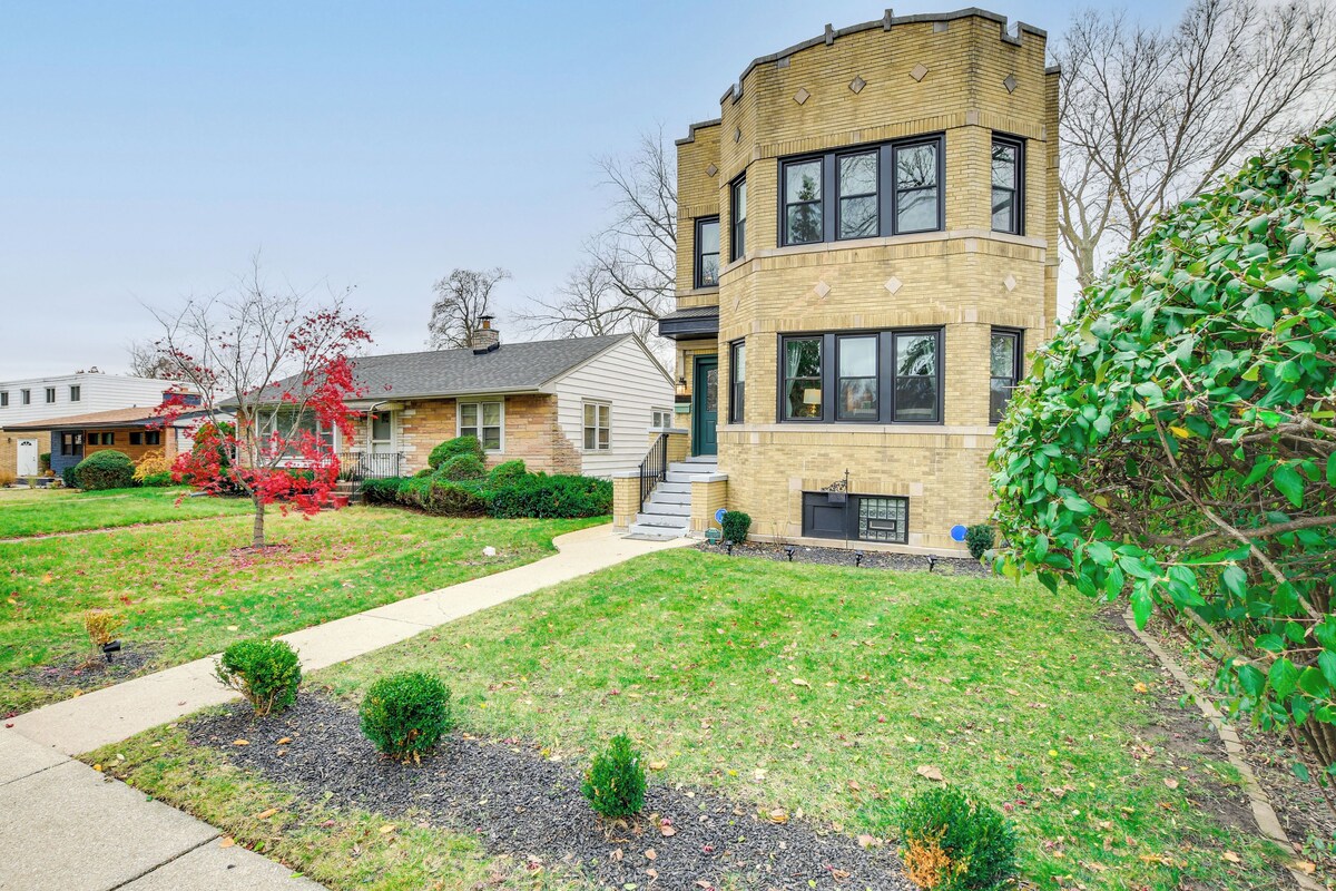 A modern two-story house with a brick facade, a front yard with a pathway, and a small garden area.